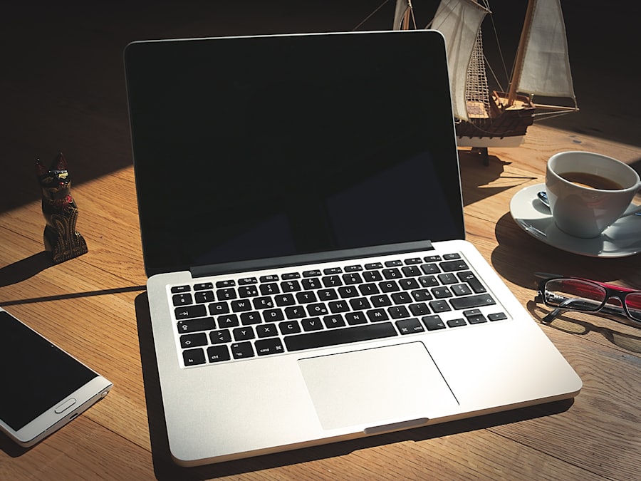 A laptop, phone and coffee cup on a wooden desk
